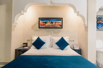 a bedroom with a bed with blue and white pillows at Riad Cologne in Marrakech