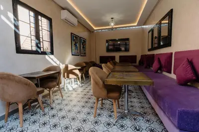 a room with a purple couch and tables and chairs at Riad Cologne in Marrakech