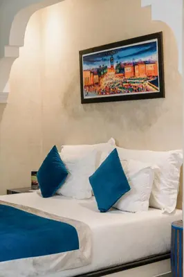 a bedroom with a bed with blue and white pillows at Riad Cologne in Marrakech