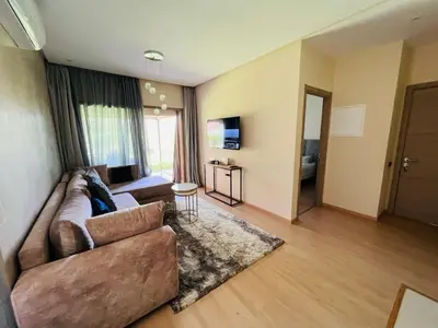 a living room with a couch and a television at Luxueux Prestigia golf city Marrakech in Marrakech