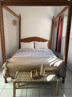 a bed with a wooden frame and a basket on a table at Riad NYAH in Marrakech