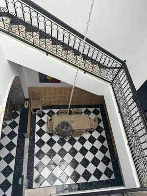 a room with a staircase with a couch on a checkered floor at Riad NYAH in Marrakech