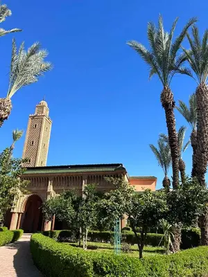 a building with a clock tower and palm trees at Riad NYAH in Marrakech