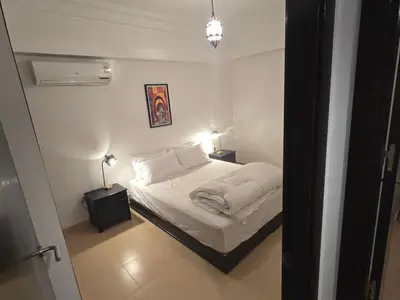 a white bedroom with a bed and two lamps at Rita 83 in Marrakech