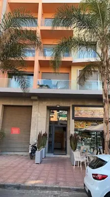 a building with a palm tree in front of it at Elegant and Modern appart hôtel with Best location in Marrakech