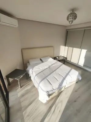 a white bedroom with a bed and a table at Appartement calme, proche de toutes commodités in Marrakech