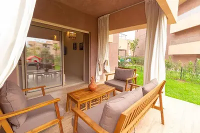 a screened in porch with a couch and chairs at Peaceful apartment with a garden in Marrakech