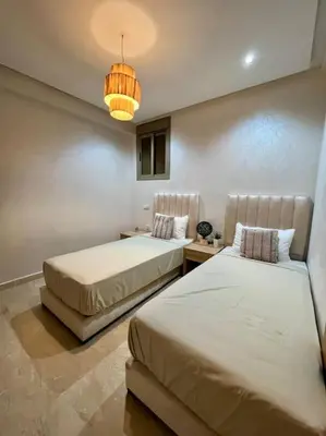 a bedroom with two beds and a chandelier at Yumo - La Vida in Marrakech