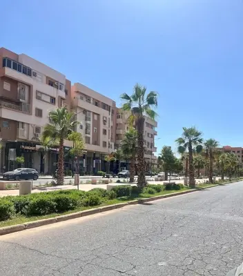 an empty street with palm trees and buildings at Yumo - La Vida in Marrakech
