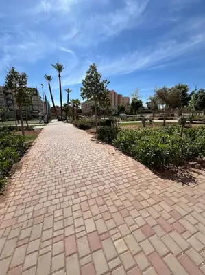a brick path in a park with palm trees at Yumo - La Vida in Marrakech