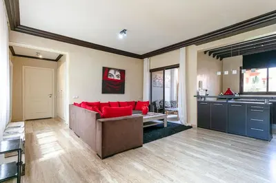a living room with a red couch and a kitchen at Zen & Chic - Marrakech Downtown in Marrakech