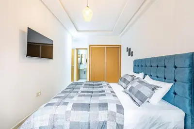 a bedroom with a large bed with a blue headboard at Appartement chic et moderne in Marrakech