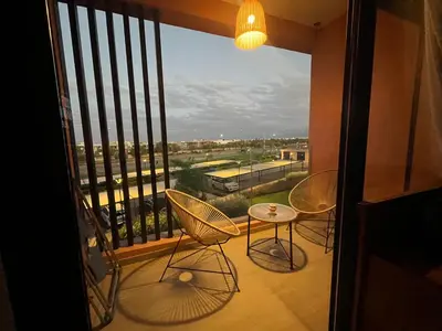 a balcony with two chairs and a table and a window at Cozy Urbain Appartement in Marrakech