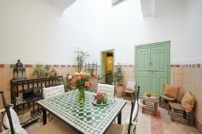 a room with a table with a vase of flowers on it at Riad Ghita Exclusif 15 min de Jemaa El Fnaa in Marrakech