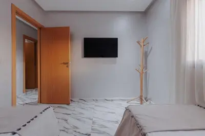 a bedroom with a television on a white wall at Zenitude séjournez en plein coeur de Marrakech in Marrakech