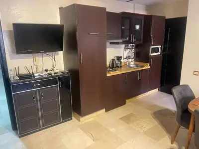 a kitchen with brown cabinets and a flat screen tv at Appartement de Lux,Guèliz in Marrakech