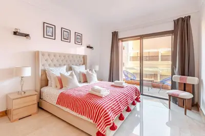 a white bedroom with a bed and a balcony at Appartement au cœur de Marrakech in Marrakech