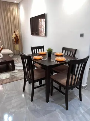 a dining room table with four chairs and a table and a television at Appartement familiale top one saada in Marrakech