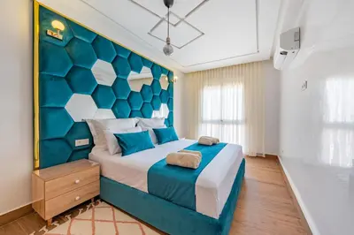 a bedroom with a large bed with a blue headboard at VISTA HOLIDAYS Warda A31 in Marrakech