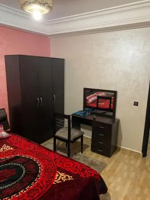 a bedroom with a bed and a desk and a chair at Résidence Sakan Ennakhil in Marrakech