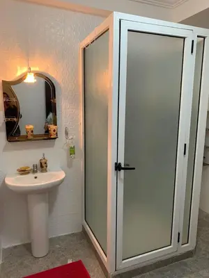 a bathroom with a sink and a glass shower door at Résidence Sakan Ennakhil in Marrakech