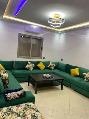 a living room with a green couch and a table at Cosy et Agréable Appartement in Marrakech