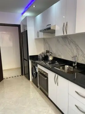 a kitchen with white cabinets and a stove top oven at Cosy et Agréable Appartement in Marrakech