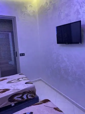 a room with a tv on the wall and a bed at Cosy et Agréable Appartement in Marrakech