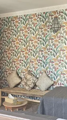a wall with a floral wallpaper with pillows on it at Riad Clefs d'Orient in Marrakech