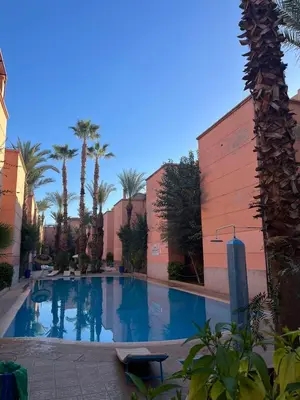 a large swimming pool with palm trees and buildings at Riyad piscine intérieure privative in Marrakech
