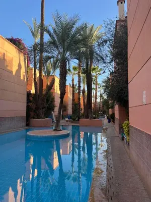 a swimming pool with palm trees next to a building at Riyad piscine intérieure privative in Marrakech