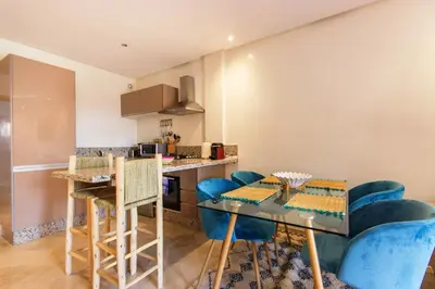 a kitchen with a glass table and blue chairs at Sumptuous appart Heart of Hivernage - Pool in Marrakech