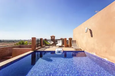 a swimming pool with chairs and a building at Sumptuous appart Heart of Hivernage - Pool in Marrakech