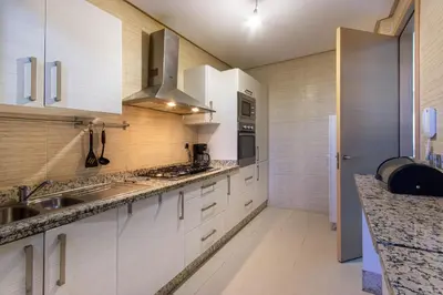 a kitchen with white cabinets and granite counter tops at Relaxation et Confort a Prestigia -10 min du centre in Marrakech
