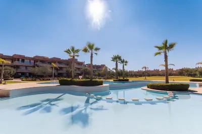 a swimming pool in a resort with palm trees at Relaxation et Confort a Prestigia -10 min du centre in Marrakech