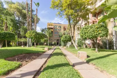 a path through a park with trees and buildings at Super cosy fully equip - pool - prox. M Avenue in Marrakech