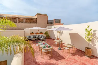 a patio with tables and chairs and umbrellas at Riad Akasia in Marrakech
