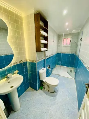 a blue tiled bathroom with a toilet and a sink at Appart Moderne Calme & Climatisé in Marrakech