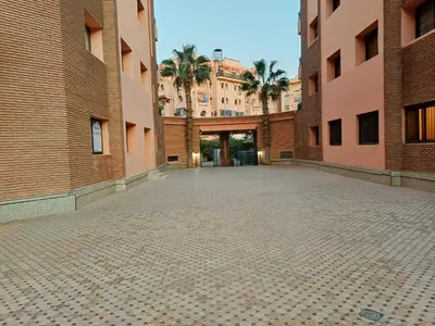 an empty courtyard with palm trees and buildings at Family Apartment with Pool in Marrakech