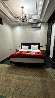 a bedroom with a large bed with a chandelier at Riad Jasmine SYBA in Marrakech