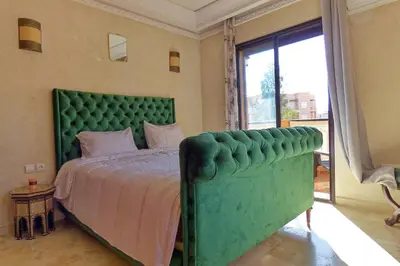 a bedroom with a green bed and a large window at Cozy & Chic Appart Haut Standing Résidence Piscine in Marrakech