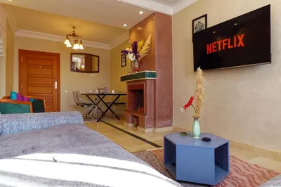 a living room with a bed and a tv on the wall at Cozy & Chic Appart Haut Standing Résidence Piscine in Marrakech