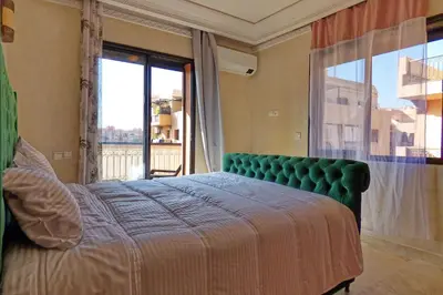 a bedroom with a green bed and a large window at Cozy & Chic Appart Haut Standing Résidence Piscine in Marrakech