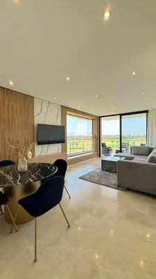 a living room with a couch and a table and chairs at Magnifique appartement prestigia in Marrakech