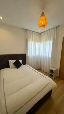 a bedroom with a large white bed and a window at Magnifique appartement prestigia in Marrakech