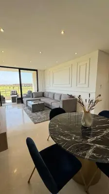 a living room with a table and a couch at Magnifique appartement prestigia in Marrakech