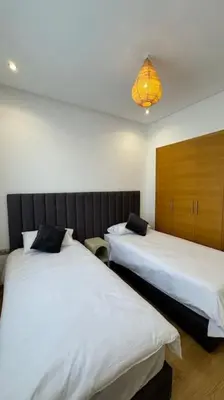 a room with two beds and a light fixture at Magnifique appartement prestigia in Marrakech