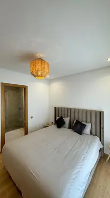 a bedroom with a large white bed and a chandelier at Magnifique appartement prestigia in Marrakech