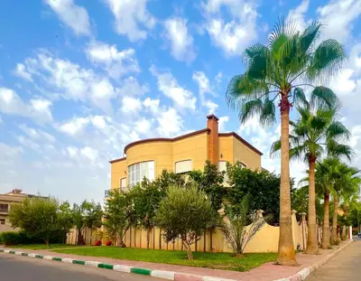 a yellow house with palm trees in front of it at Villa La Baraka in Marrakech