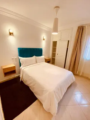 a bedroom with a white bed with a blue headboard at Appart Moderne Calme & Climatisé in Marrakech